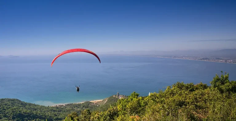 Tandem paraglider soaring over the Cape Town coastline from Signal Hill.